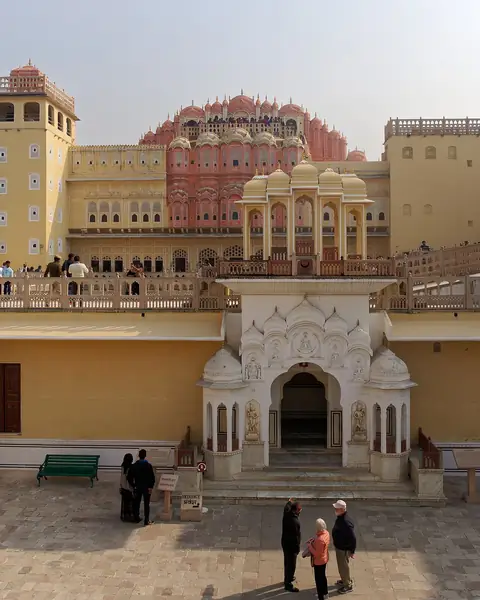 The pink, many-windowed facade of a palace rising behind a courtyard
